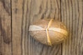 Handcrafted decorative Easter egg wrapped in craft paper tied with twine on plank wood background