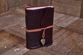 Handcrafted Leather Journal with Leaf Charm on Wooden Surface Royalty Free Stock Photo