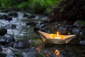 handcrafted paper boat with a candle inside set ablaze on a creek