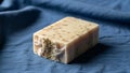 A handcrafted soap bar rests on a blue fabric. The soap is rectangular with an off-white color, Royalty Free Stock Photo