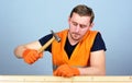 Handcrafting concept. Carpenter, woodworker on concentrated face hammering nail into wooden board. Man, handyman in Royalty Free Stock Photo