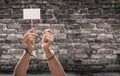 Handcuffed Female Hand Holding Blank Sign Against Aged Brick Wall Royalty Free Stock Photo