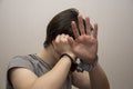 A handcuffed teenager covers his face with his hands on a gray background, medium plan. Juvenile delinquent, criminal liability of Royalty Free Stock Photo