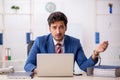 Handcuffed young male employee sitting in the office