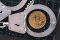 Handcuffs and bitcoin on a laptop keyboard, top view. Concept on the topic of punishment for mining digital currency Royalty Free Stock Photo