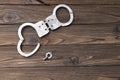 Handcuffs for detaining criminals, key, on a wooden background