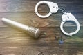 Handcuffs for the detention of delinquents with a microphone against the background of a wooden table. Royalty Free Stock Photo