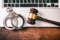 Handcuffs and a gavel on a computer on a wooden background, copy space. Royalty Free Stock Photo