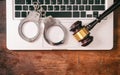 Handcuffs and a gavel on a computer on a wooden background, copy space. Royalty Free Stock Photo