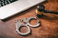 Handcuffs and a gavel and a computer on a wooden background. Royalty Free Stock Photo