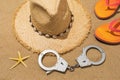 Handcuffs, hat, slippers and starfish on the sand, concept on the theme of punishment for theft on the beach Royalty Free Stock Photo