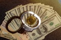 Handcuffs on hundred dollar bills and a gold bitcoin coin. Top view