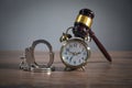 Handcuffs, judge gavel and alarm clock on the wooden background Royalty Free Stock Photo