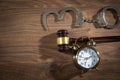 Handcuffs, judge gavel and alarm clock on the wooden background