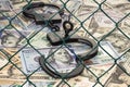 Handcuffs with the key on the background of dollars under wire netting (lattice)