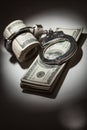 Handcuffs Locked on Roll of One Hundred Dollar Bills Under Spotlight Royalty Free Stock Photo