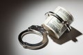 Handcuffs on Roll of One Hundred Dollar Bills Under Spotlight Royalty Free Stock Photo