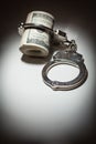 Handcuffs on Roll of One Hundred Dollar Bills Under Spotlight Royalty Free Stock Photo