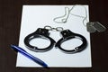 handcuffs and military badges lying on a white sheet of paper, and a blue ballpoint pen. Concept: law and justice, Royalty Free Stock Photo
