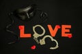 Handcuffs for sex games and hearts on black background. Sexual bdsm toy