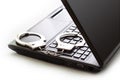 A handcuffs standing on laptop computer keyboard. Royalty Free Stock Photo