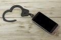 Handcuffs and telephone on the background of a wooden texture. mock up Dependence on the smartphone, the Internet. Royalty Free Stock Photo