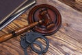 Handcuffs and a wooden gavel in front of manila folders