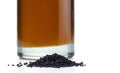 A handful of black cumin seeds on the background of a glass bottle with black seed oil. Royalty Free Stock Photo