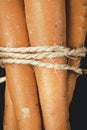 Handful of carrots tied with hemp rope on black background