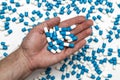 a handful of medicines on the palm, against the background of white-blue capsules Royalty Free Stock Photo