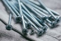 A handful of metallic self-cutters screws lies against the backdrop of an old denim fabric. Selective focus shot with
