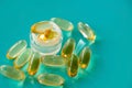 A handful of omega 3 capsules with a glass beaker on a blue background