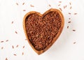 handful of raw red rice in the wood bowl in the shape of heart on white stone background Royalty Free Stock Photo