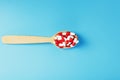 A handful of Red and white pill capsules in a wooden spoon on a blue background Royalty Free Stock Photo