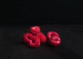 A handful of ripe raspberries on a black wooden table