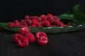 A handful of ripe raspberries on a black wooden table