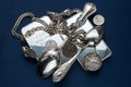 A handful of silver bullion, silverware, jewelery and old silver coins on a dark blue background