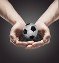 A handful soil with classic soccer ball in the man