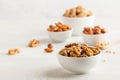 A handful of walnuts in a white bowl, assorted nuts on a light background. Healthy snacks, healthy fats. Copy space