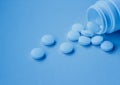 A handful of white large tablets on a blue background, vitamins