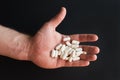 A handful of white pills, vitamins in the left hand on black background. Bless you. Take care of your body and health. Photo with Royalty Free Stock Photo
