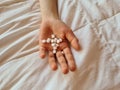 Handful of white round pills in child palm on bed. Hand holds bunch of small round medicines Royalty Free Stock Photo