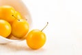 Handful of yellow cherry plums in ceramic bowl