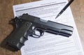 1911 handgun and pen with firearm purchase paperwork