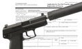 Handgun wearing a silencer in front of public domain tax form to make a purchase
