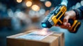 Handheld barcode scanner reading a shipping label on a cardboard package inside a busy warehouse Royalty Free Stock Photo