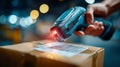 Handheld barcode scanner reading a shipping label on a cardboard package inside a busy warehouse Royalty Free Stock Photo