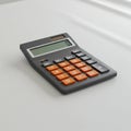 A handheld calculator with a black casing and orange buttons lies on a white surface. Royalty Free Stock Photo