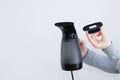 Handheld garment steamer and removable brush in the hand of  Caucasian woman. White background Royalty Free Stock Photo