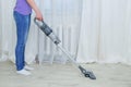 Handheld gray vacuum cleaner in the hand of standing caucasian woman. Vacuum the floor in the room